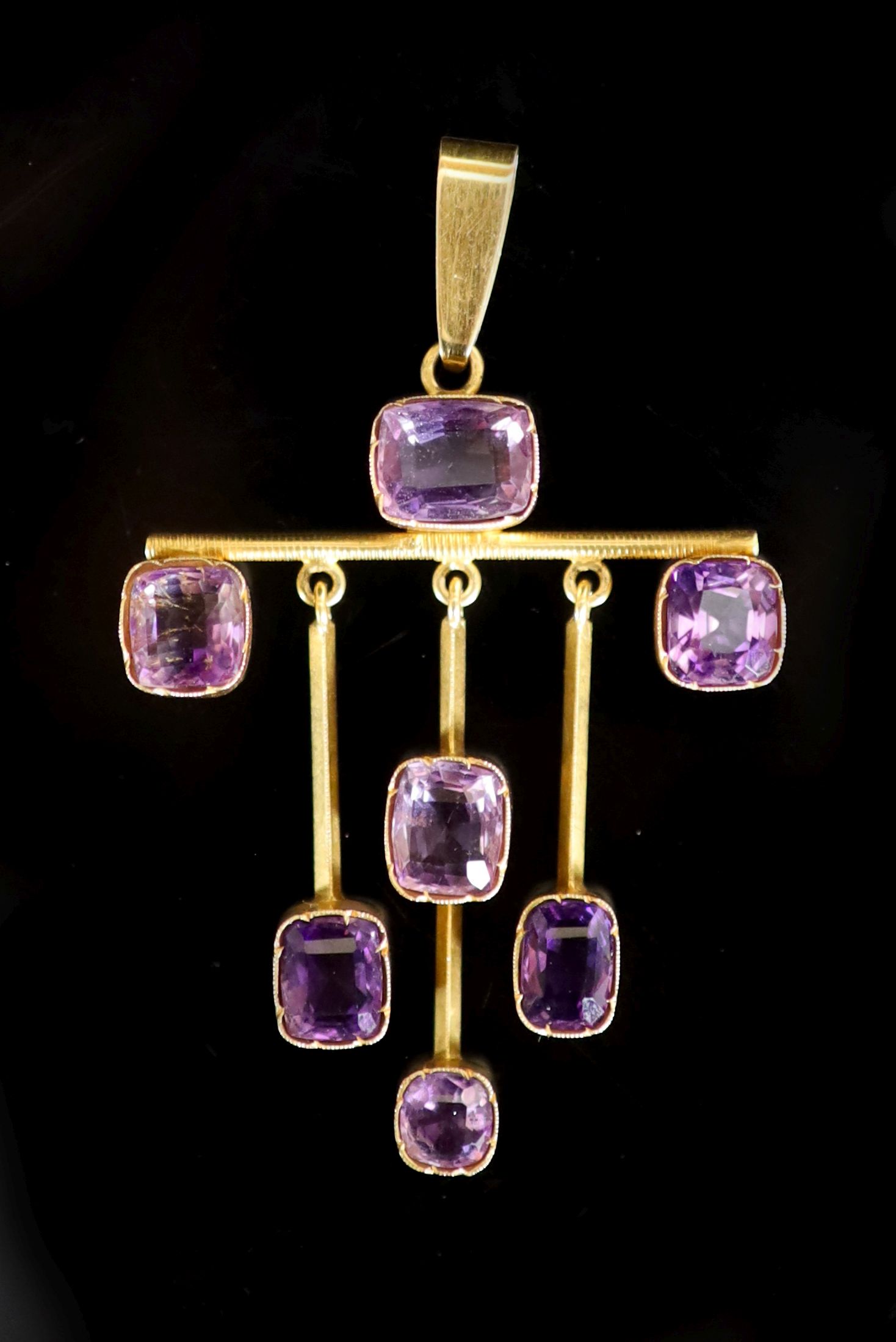 A stylish early 20th century gold and seven stone amethyst set drop pendant